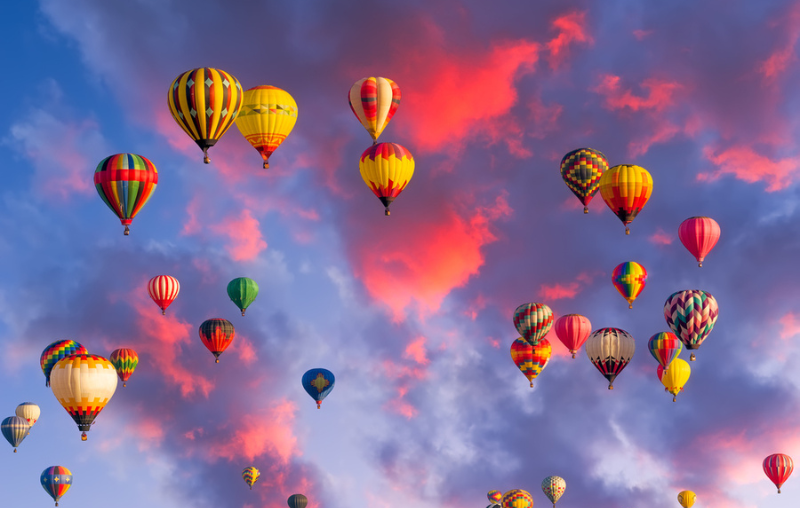 Colorful hot air balloons in flight illuminated by early morning light