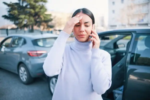Distressed woman on phone after car accident in parking lot