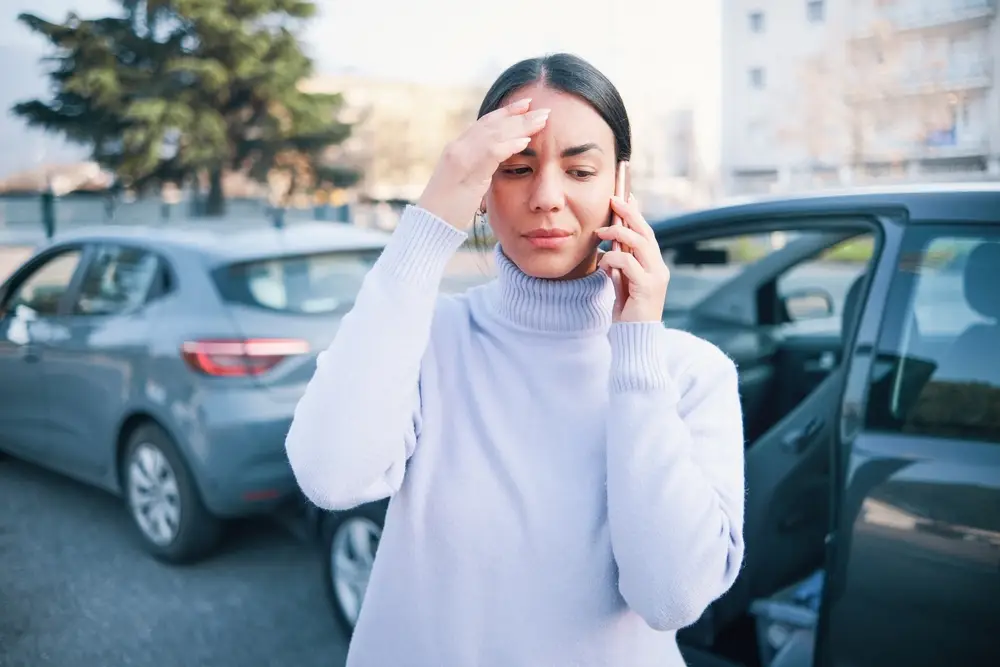 Distressed woman on phone after car accident in parking lot