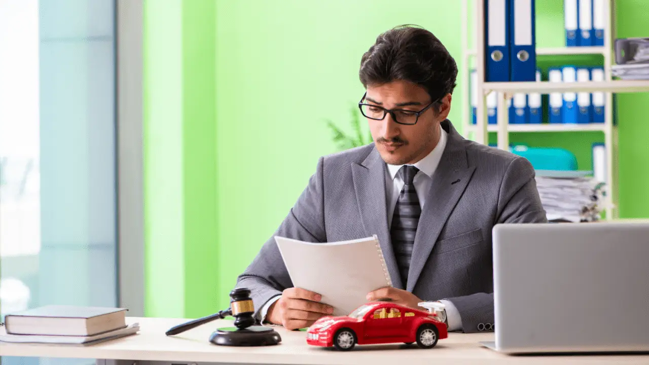 Personal injury lawyer reviewing car accident settlement timeline documents with red toy car and gavel on desk