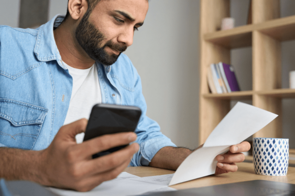 Man using car accident settlement calculator florida on phone while reviewing documents