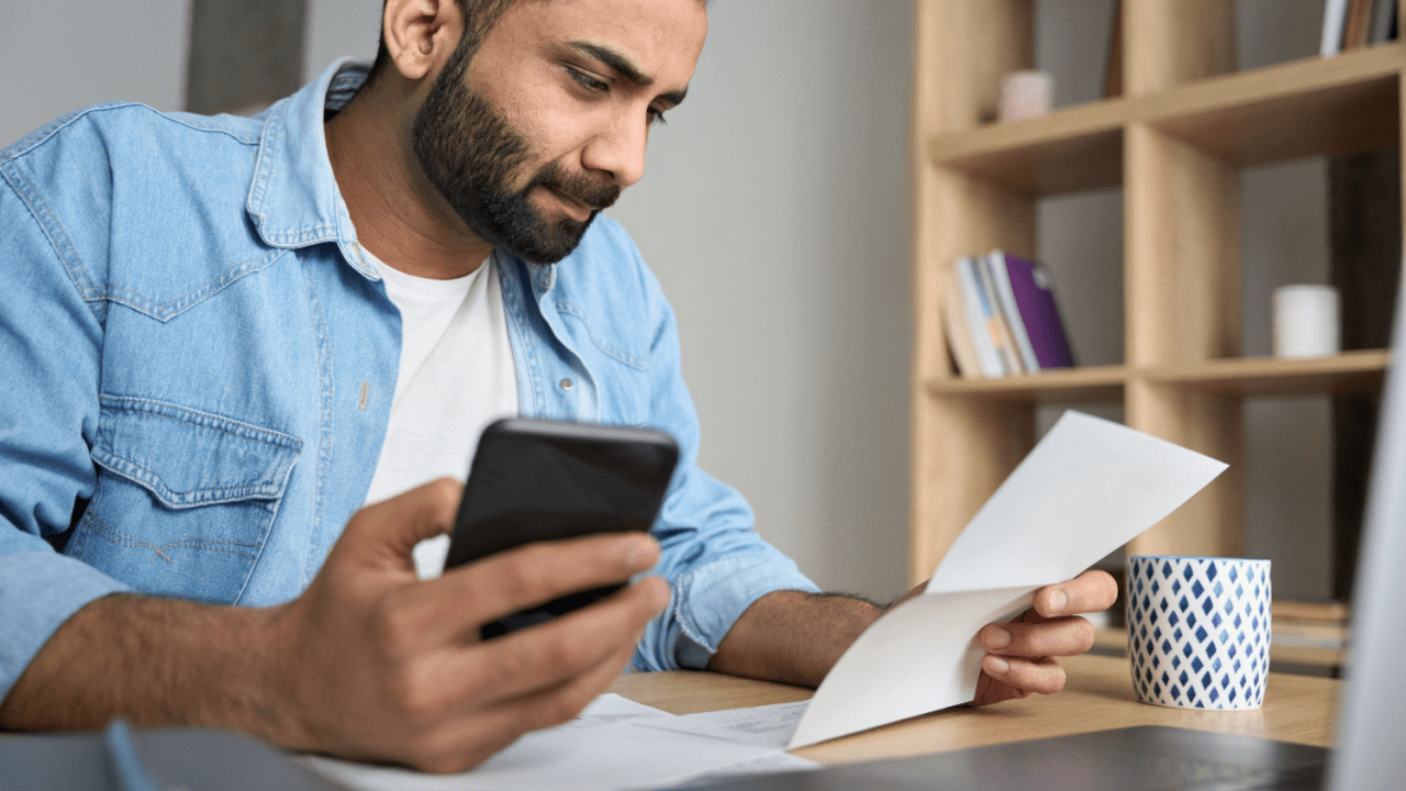 Man using car accident settlement calculator florida on phone while reviewing documents