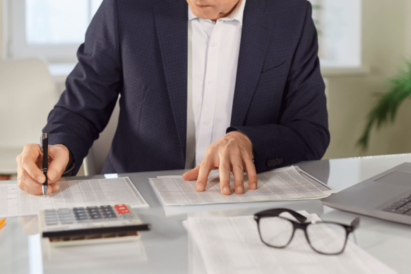 Professional using car accident settlement calculator with documents and calculator on desk