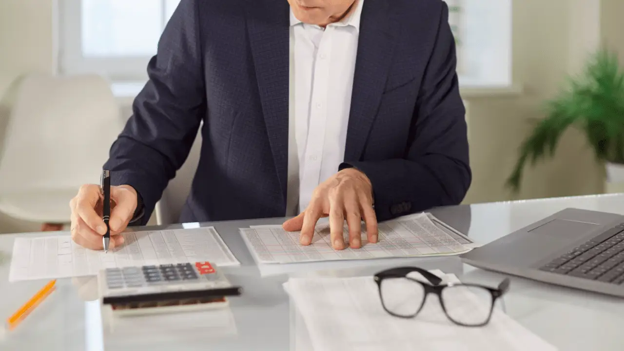 Professional using car accident settlement calculator with documents and calculator on desk