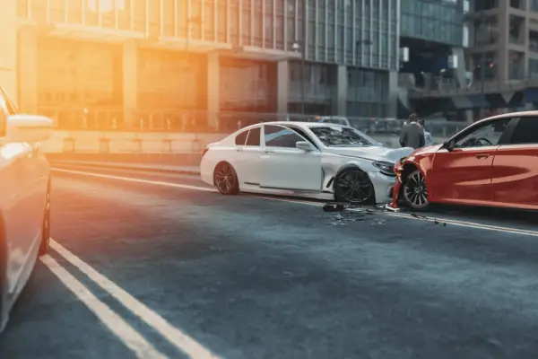 Car accident scene with damaged red and white vehicles after collision showing cracked windshield and road debris