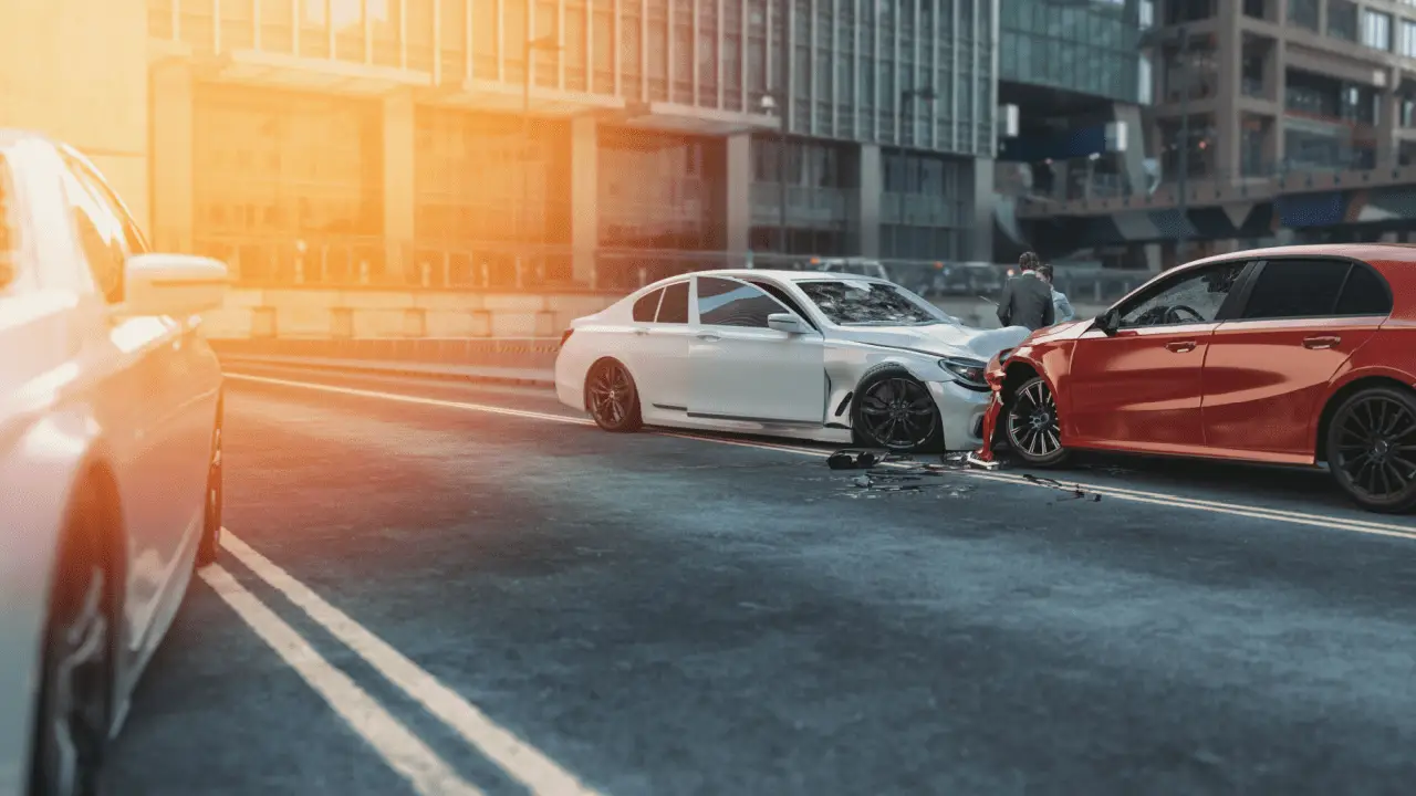 Car accident scene with damaged red and white vehicles after collision showing cracked windshield and road debris