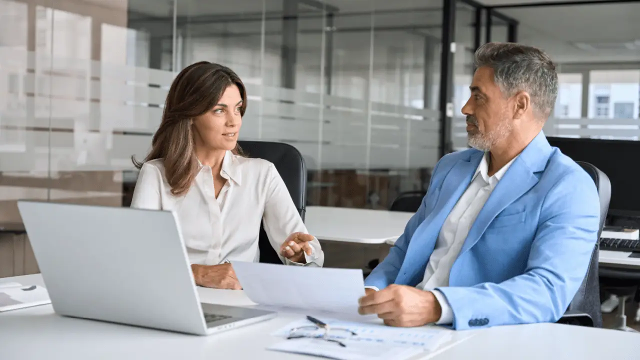 Personal injury lawyer consulting with client about car accident settlement estimate in modern office
