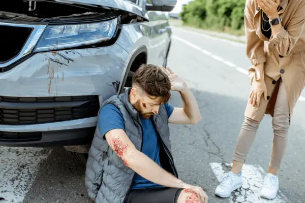 Injured man sitting on road after a crash — do most people sue after a car accident?