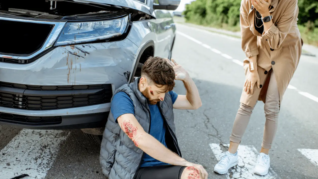 Injured man sitting on road after a crash — do most people sue after a car accident?