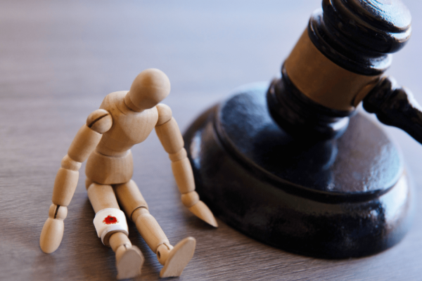 Injured wooden figure beside judge’s gavel — do most personal injury cases win?