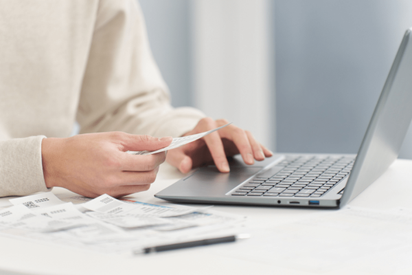Person using laptop computer while reviewing legal documents and settlement paperwork on desk
