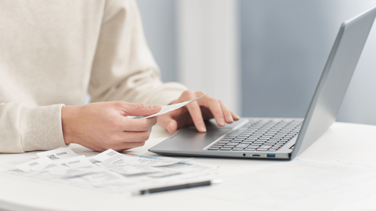 Person using laptop computer while reviewing legal documents and settlement paperwork on desk