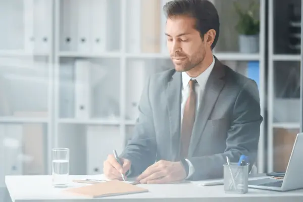 Professional attorney in gray suit writing legal documents at office desk while client considers can I sue my lawyer for pain and suffering malpractice claim