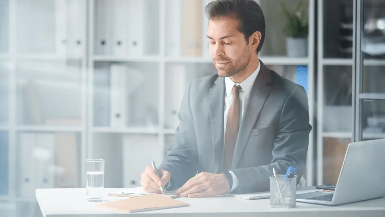 Professional attorney in gray suit writing legal documents at office desk while client considers can I sue my lawyer for pain and suffering malpractice claim