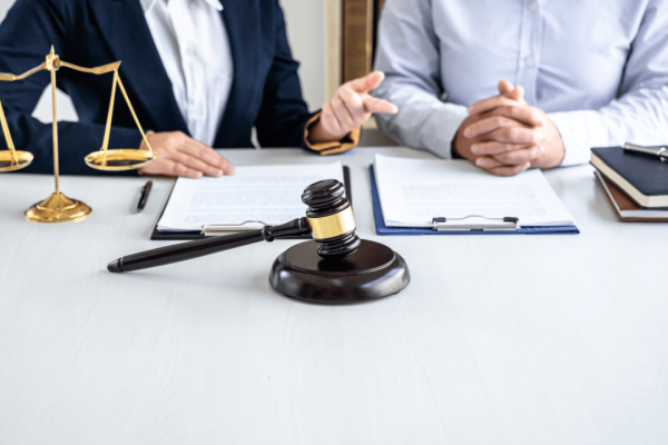 Injury lawyers prepare legal documents during client consultation with gavel and scales of justice on desk