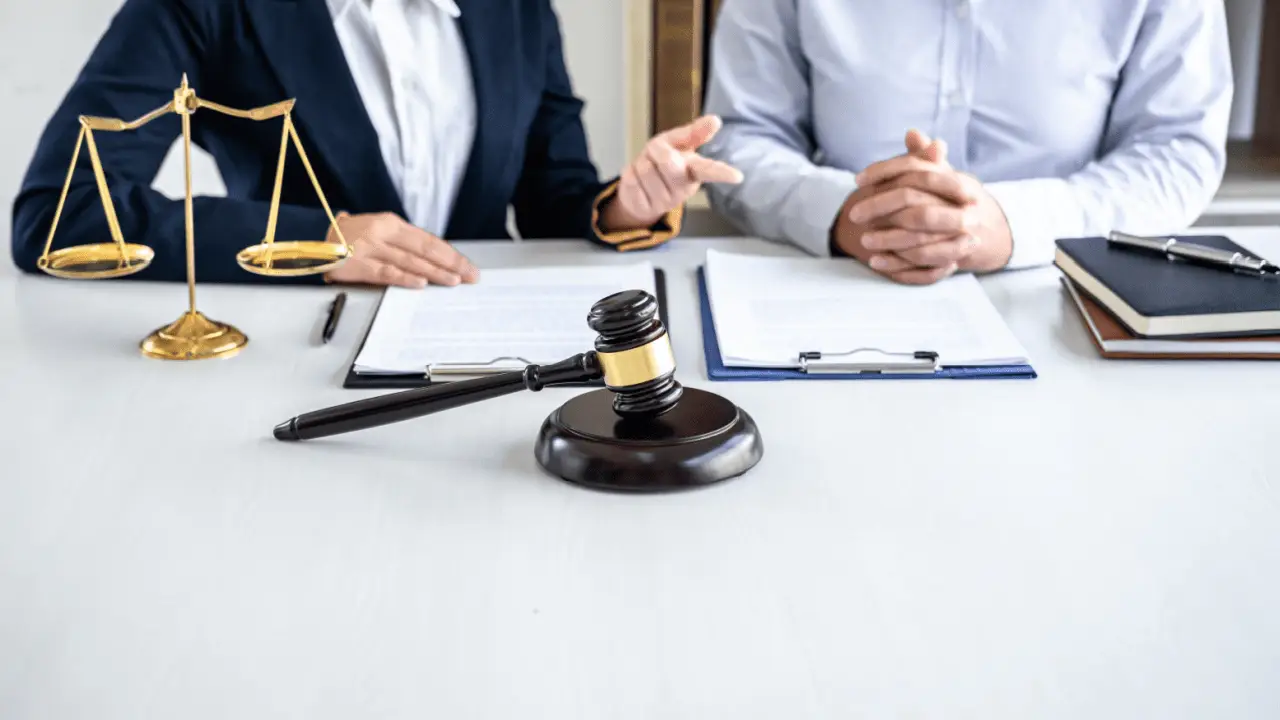 Injury lawyers prepare legal documents during client consultation with gavel and scales of justice on desk