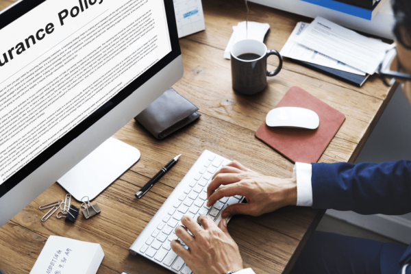 Professional reviewing insurance policy document while researching how do insurance companies determine settlement amounts on computer