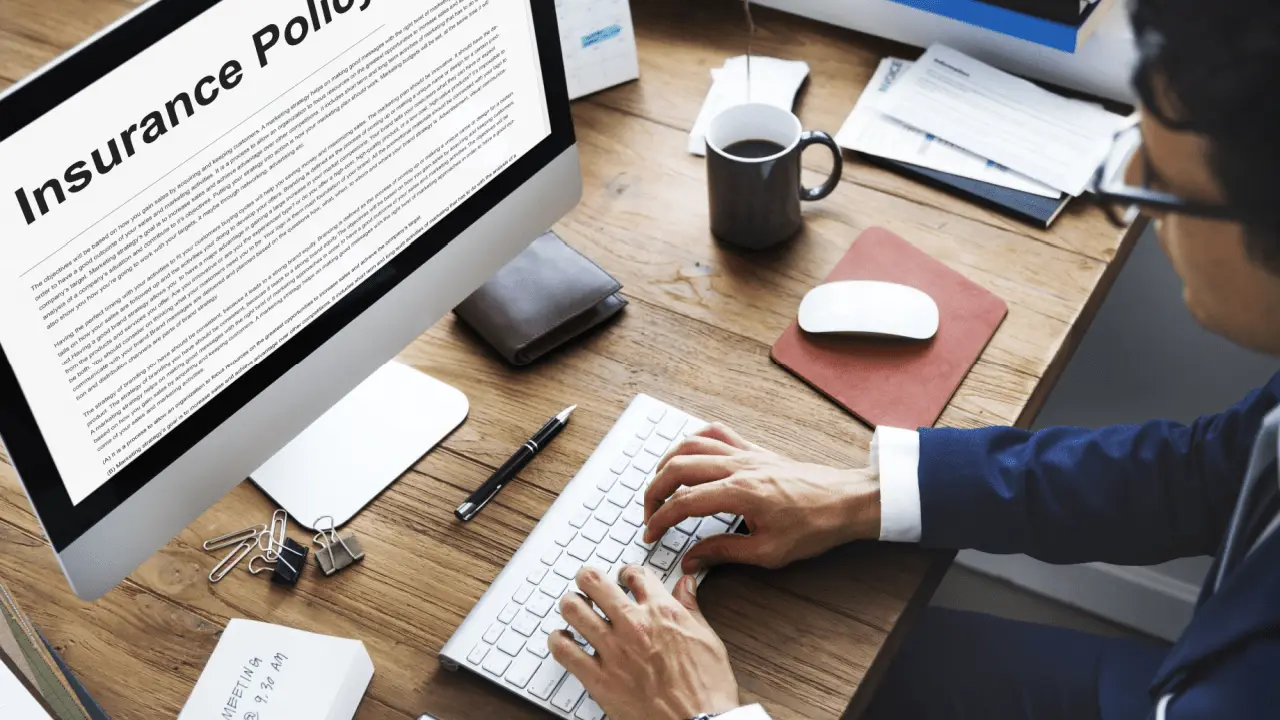 Professional reviewing insurance policy document while researching how do insurance companies determine settlement amounts on computer