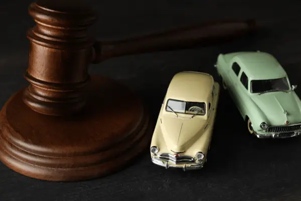 Wooden gavel next to vintage toy cars representing how hard it is to win a car accident lawsuit