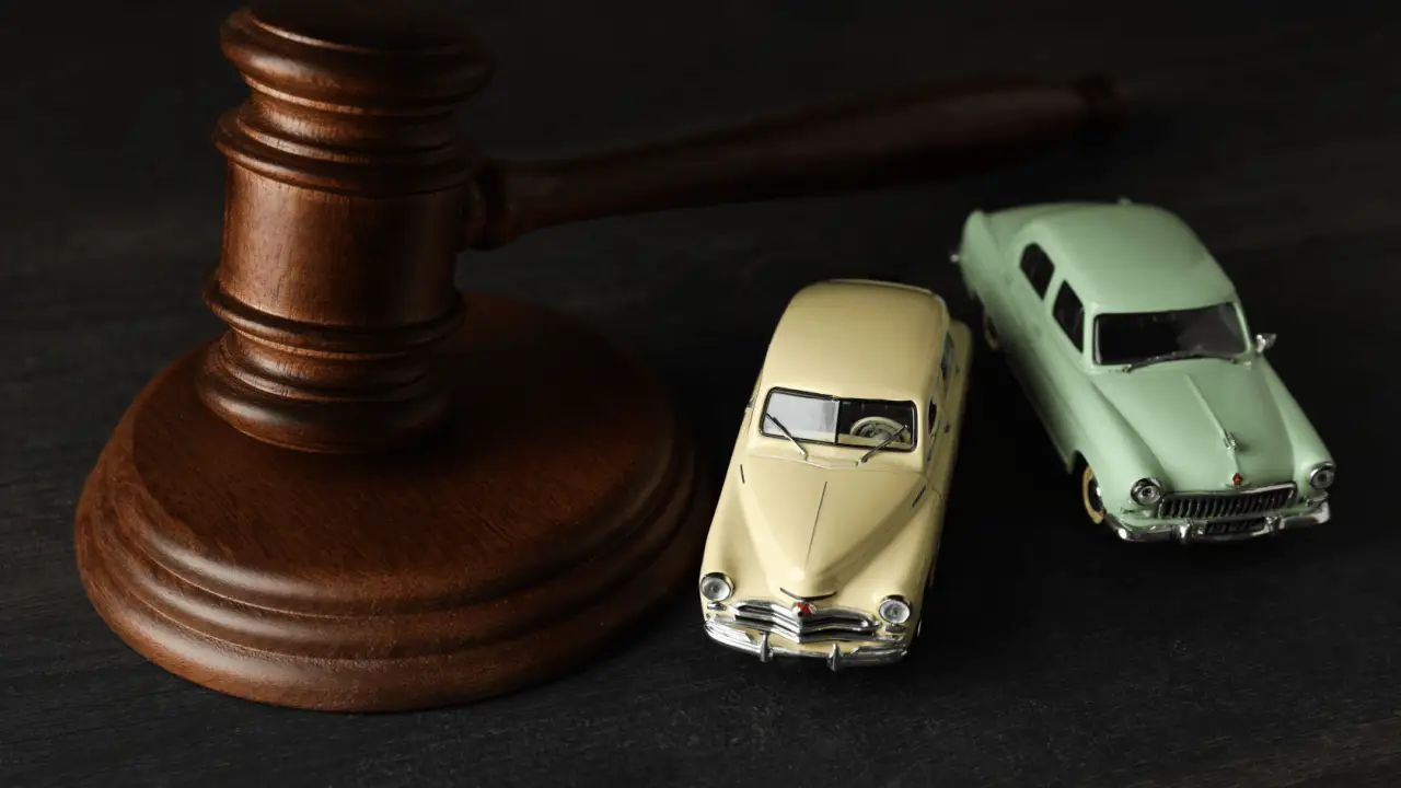 Wooden gavel next to vintage toy cars representing how hard it is to win a car accident lawsuit