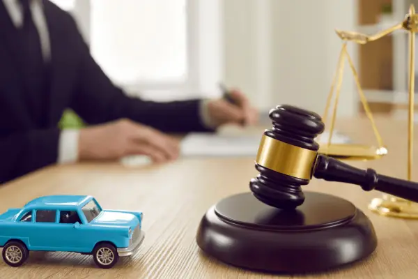 Oregon car accident settlement timeline with gavel scales of justice and blue toy car representing how long you have to settle a car accident in Oregon