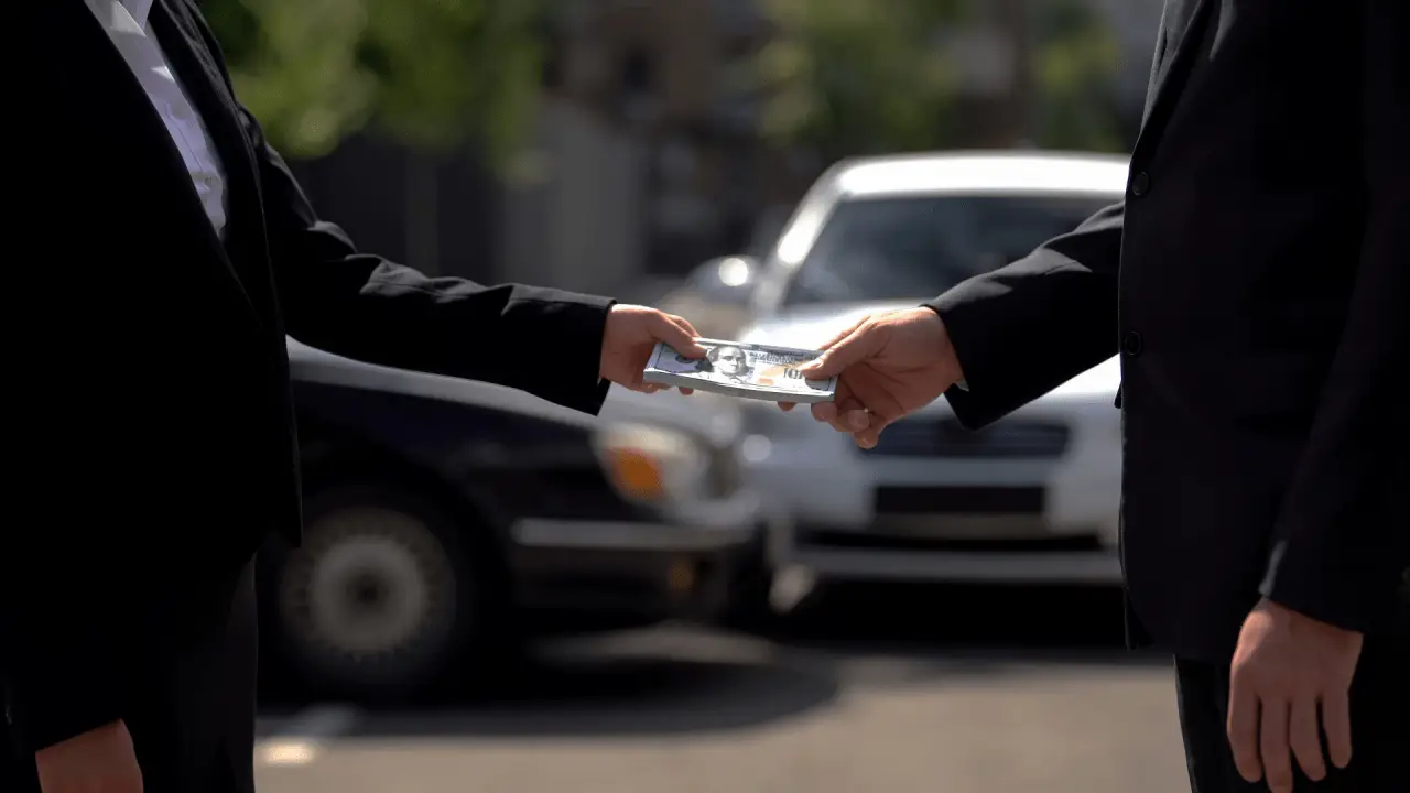 Two professionals exchanging settlement money showing how to get more money from a car accident settlement