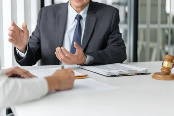 Professional attorney in business suit gesturing during legal consultation with client about how to get the most out of an injury claim with gavel on desk