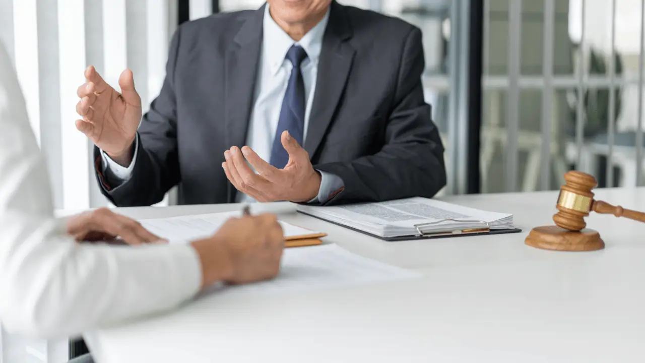 Professional attorney in business suit gesturing during legal consultation with client about how to get the most out of an injury claim with gavel on desk