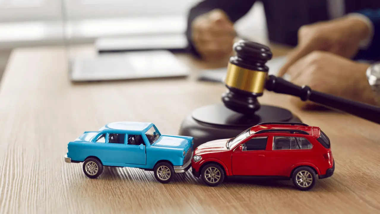 Two toy cars positioned after collision with judge gavel representing should I ask for more in a car accident lawsuit legal decisions