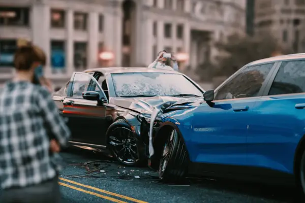 Car accident scene showing damaged vehicles where drivers wonder should I call lawyer or insurance first