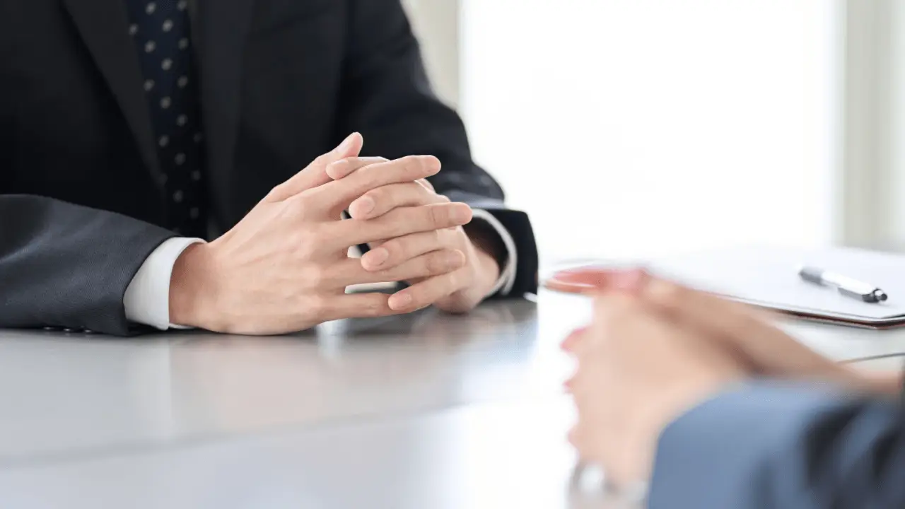 Professional attorney in dark suit with clasped hands during client consultation discussing does an injury lawyer go to court for you representation