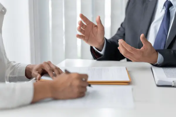Professional attorney in gray suit gesturing with hands while explaining how do you talk to your lawyer for a car accident during client consultation