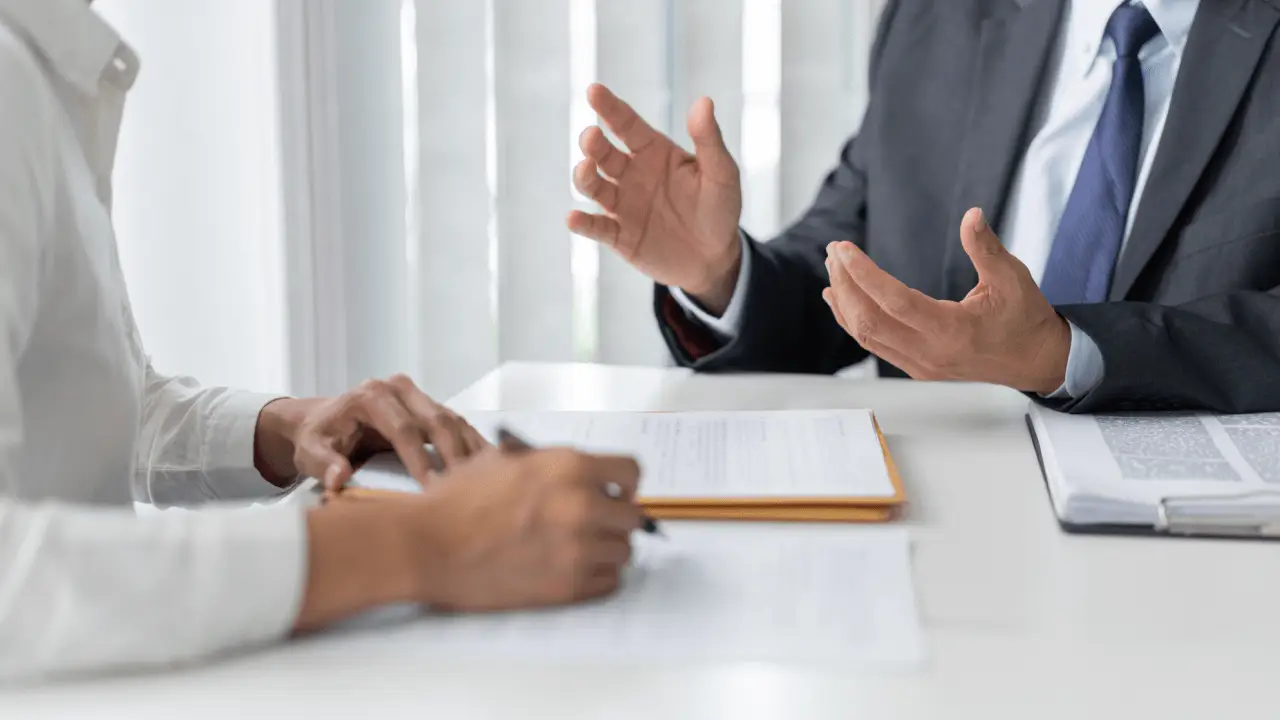 Professional attorney in gray suit gesturing with hands while explaining how do you talk to your lawyer for a car accident during client consultation