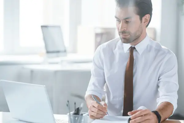 Professional attorney in white shirt and brown tie working at desk with laptop reviewing documents about can a personal injury lawyer drop your case