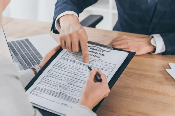 Person completing workers compensation claim form with attorney guidance for maximum compensation recovery