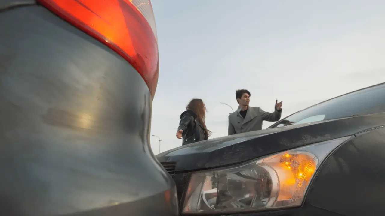 Two people standing near damaged vehicles after a car accident with visible vehicle damage and amber warning lightsTwo people standing near damaged vehicles after a car accident with visible vehicle damage and amber warning lights