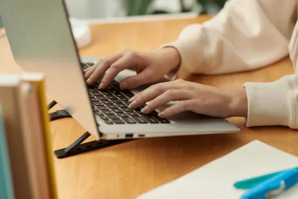 Person researching average payout for minor car accident while typing on laptop at wooden desk with documents