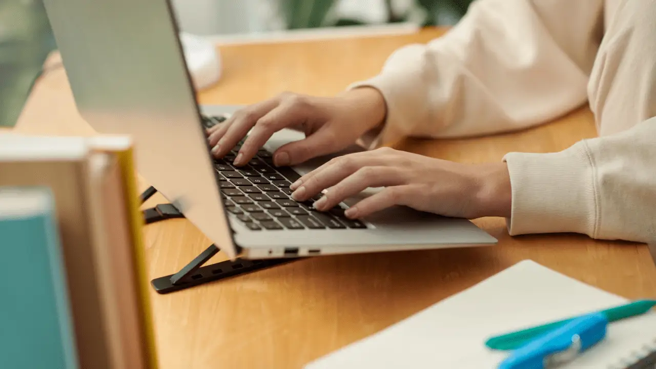 Person researching average payout for minor car accident while typing on laptop at wooden desk with documents