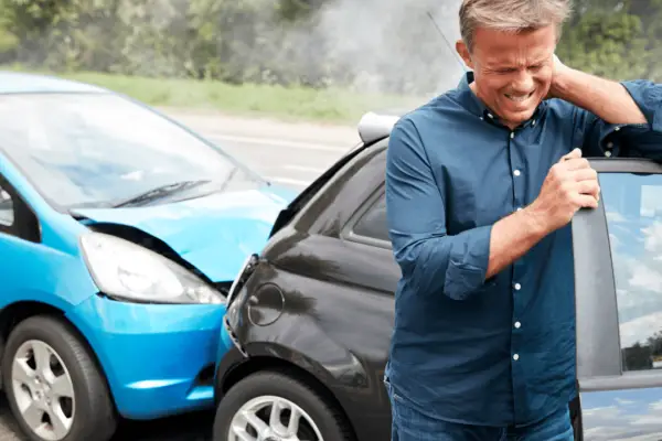 Man holding neck after car accident showing whiplash injury that leads to average settlement for whiplash car accident claims