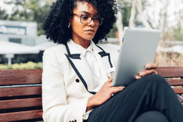 Woman researching can I be sued personally after a car accident on tablet while sitting on park bench