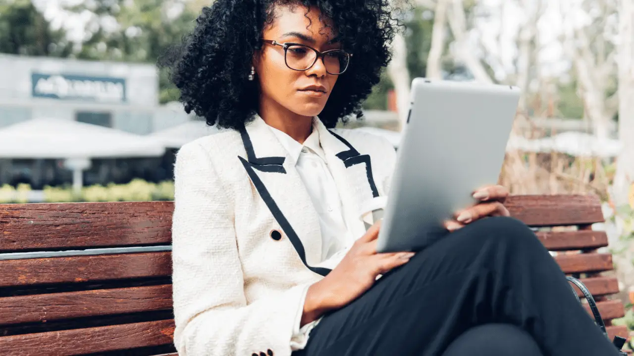 Woman researching can I be sued personally after a car accident on tablet while sitting on park bench