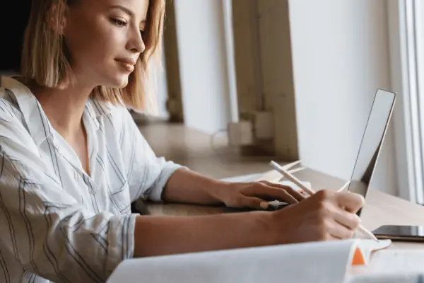 Young woman researching how long after a car accident do you get a settlement while taking notes on laptop at home