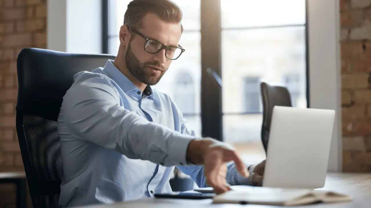 Professional businessman researching how to choose the best car accident lawyer while working on laptop in modern office