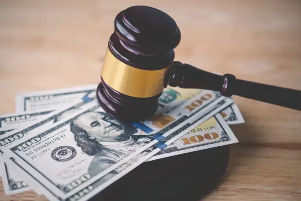 Judge gavel resting on hundred dollar bills representing how much are most car accident settlements