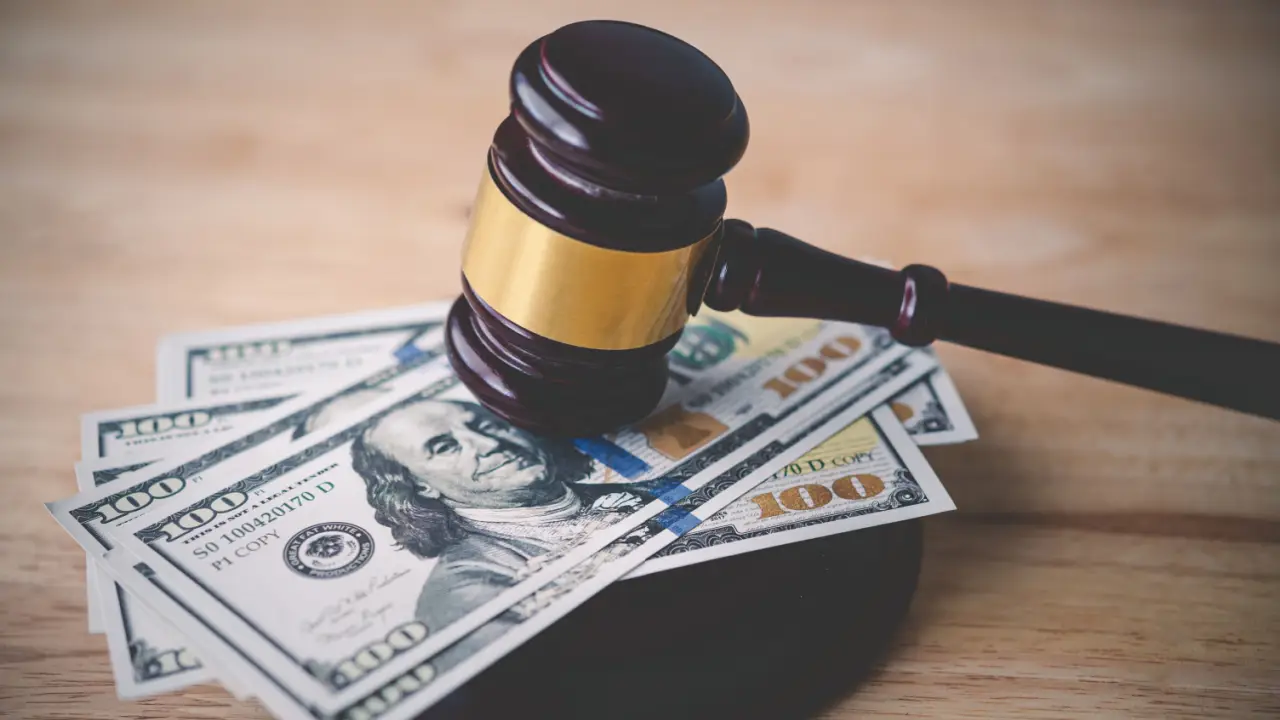 Judge gavel resting on hundred dollar bills representing how much are most car accident settlements