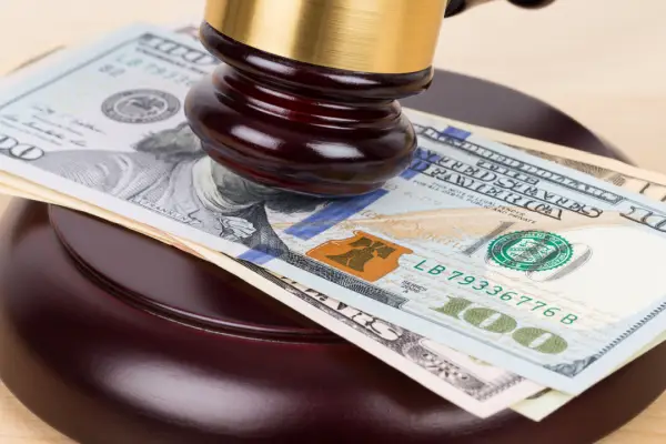 Judge gavel on stack of hundred dollar bills representing how much of a 30k settlements will i get after legal fees