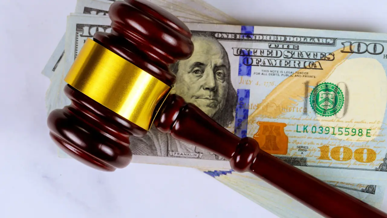 Judge gavel on hundred dollar bills representing how much should I ask for a settlement decisions