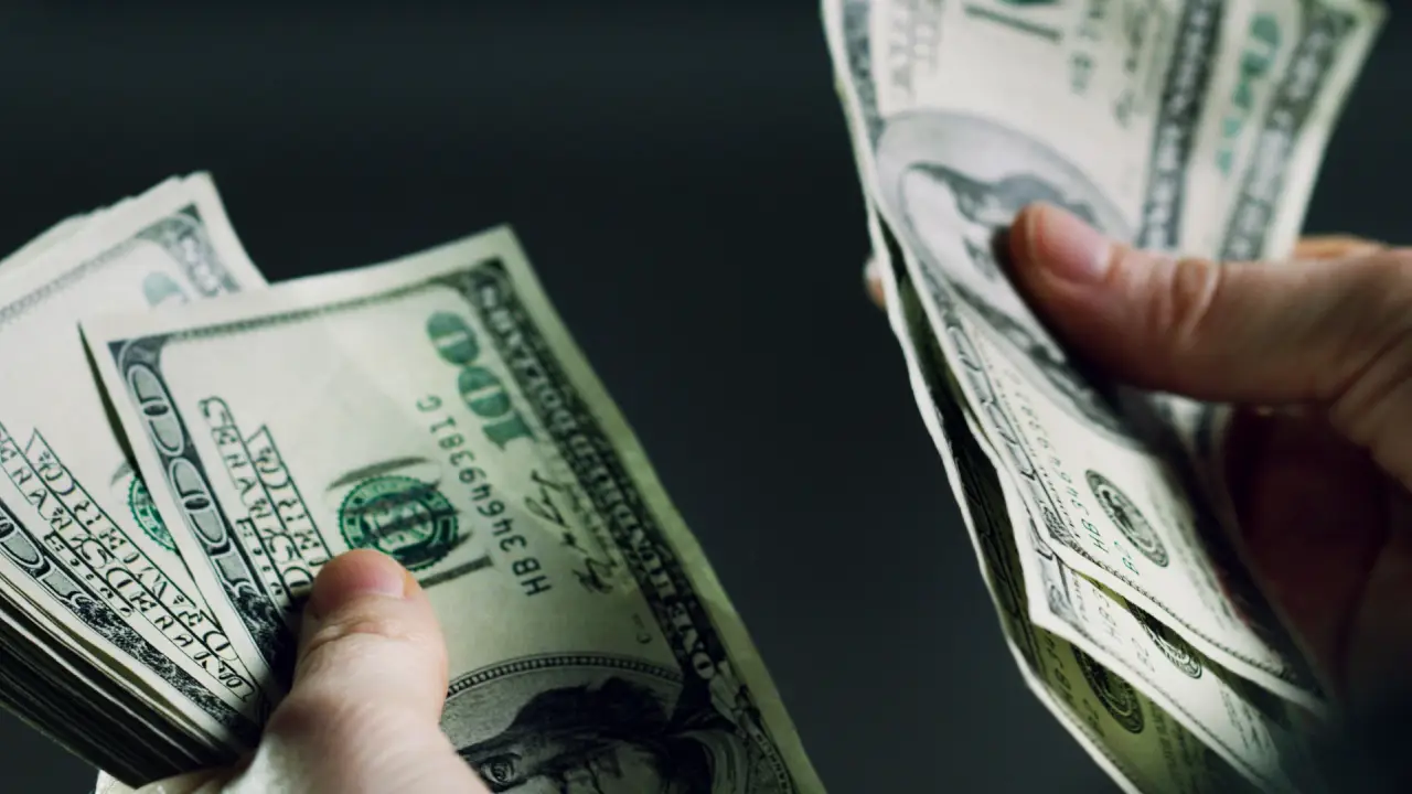 Person counting cash settlement money representing how much should you get if you get hit by a car compensation