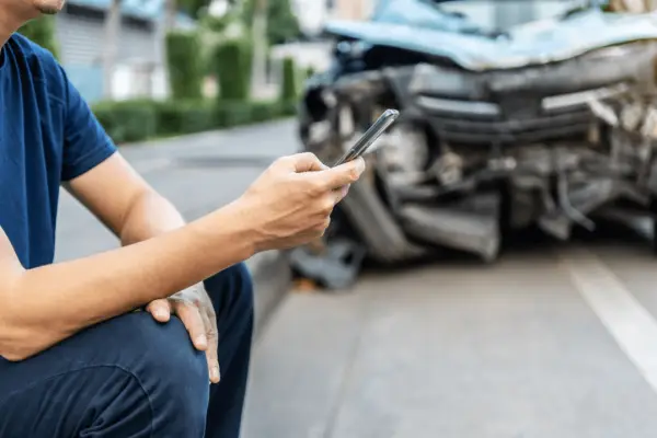 Man using phone to document car accident for injury claim settlement without lawyer