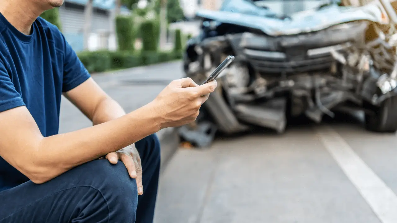 Man using phone to document car accident for injury claim settlement without lawyer